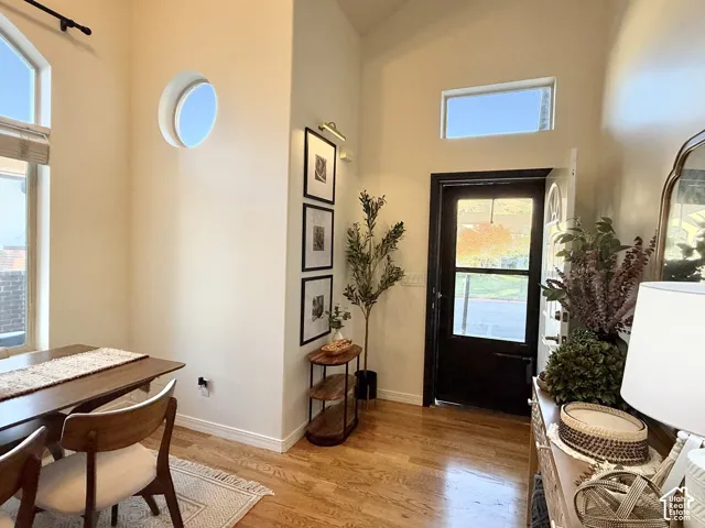 Entryway featuring vaulted ceilings, wood-finish flooring, a circular accent window, a transom window, and a dark-toned entry door with glass paneling