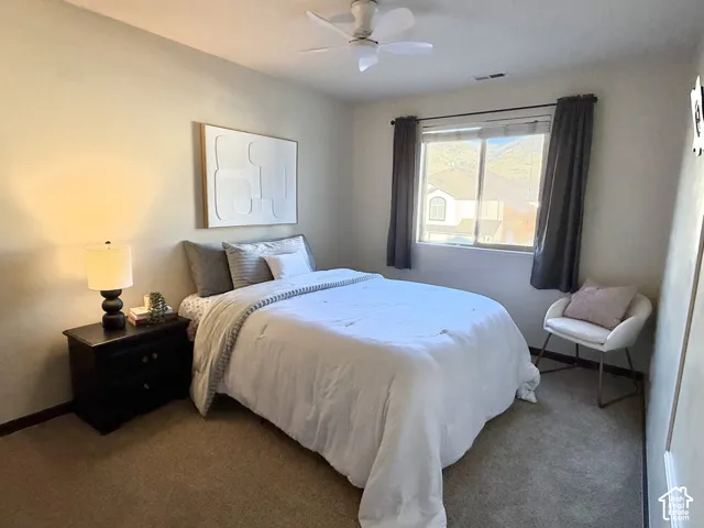 Neutral wall-to-wall carpeting, ceiling fan with light fixture, and window with natural light