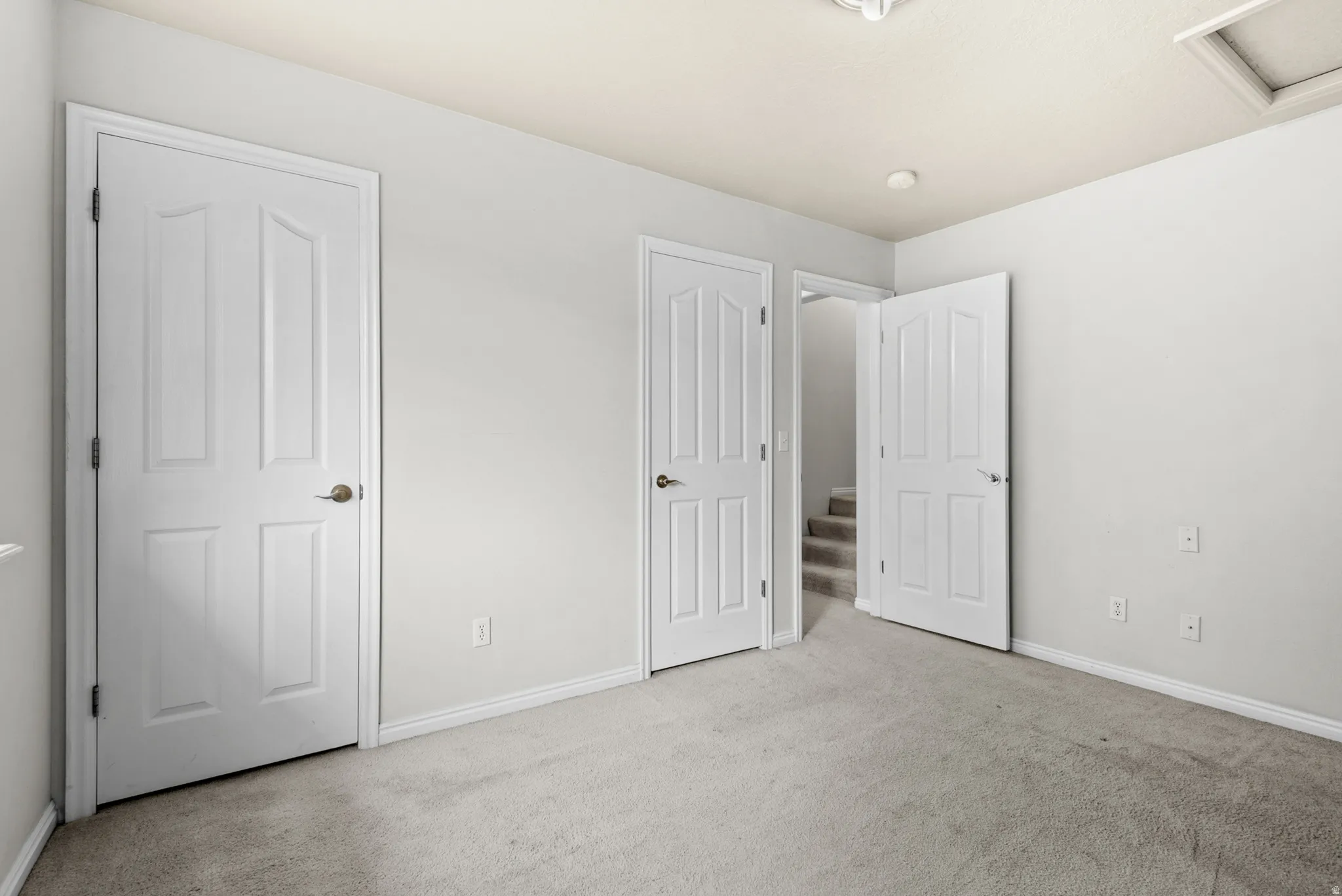 Carpeted room featuring light gray walls, white baseboards, and multiple paneled doors