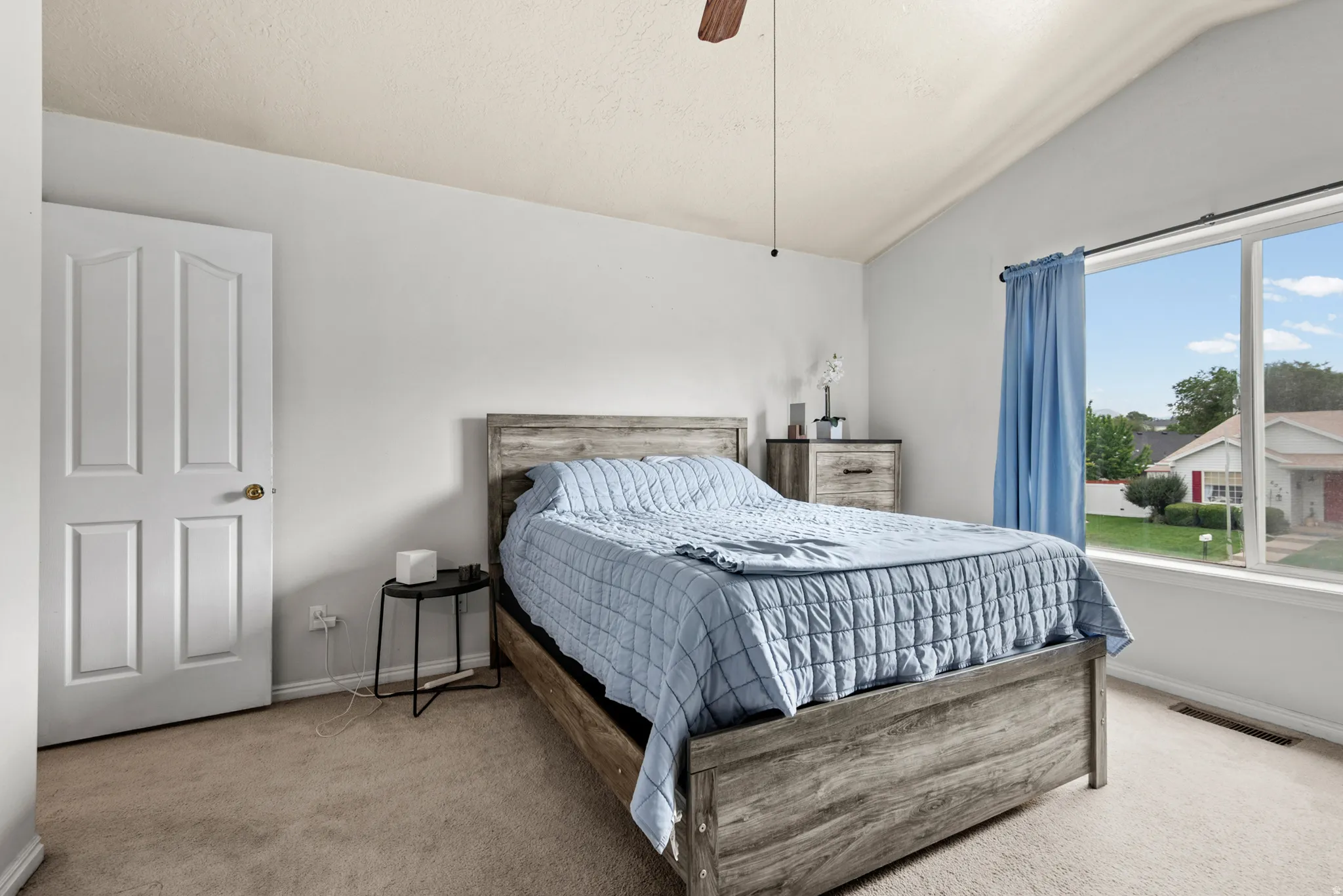 Bedroom with vaulted ceilings, large picture window, and carpeted flooring