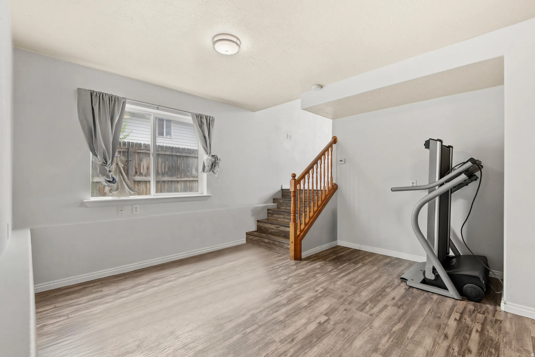 Interior space featuring wood-finish flooring, a double-paned window, and a wooden staircase with a balustrade