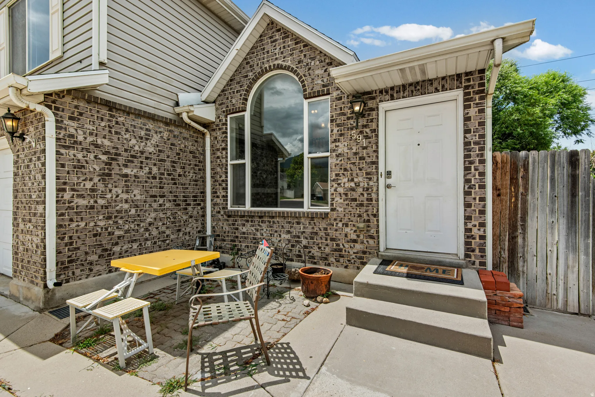 Brick façade exterior with arched window detail, a covered entry, and concrete steps