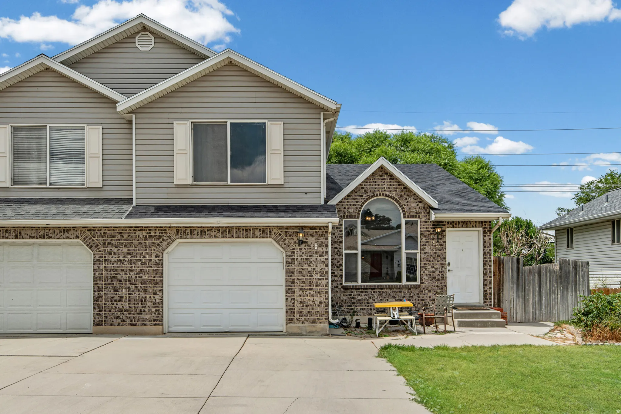 Brick and siding exterior featuring an arched window, two garage doors, and a front entry