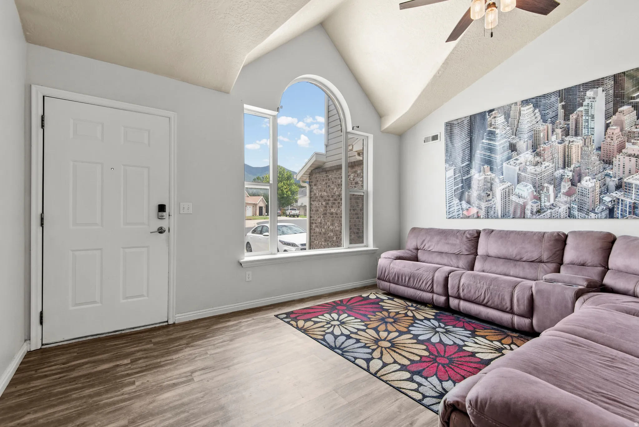 Vaulted ceilings with a ceiling fan, wood-finish flooring, and natural light from arched and rectangular windows