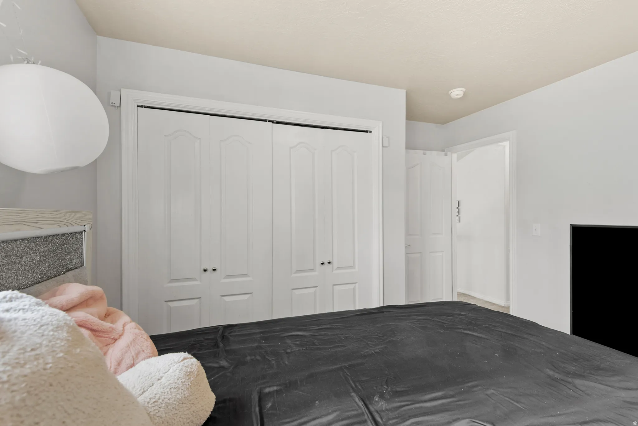 White bi-fold closet doors with black hardware, light gray walls, and textured ceiling