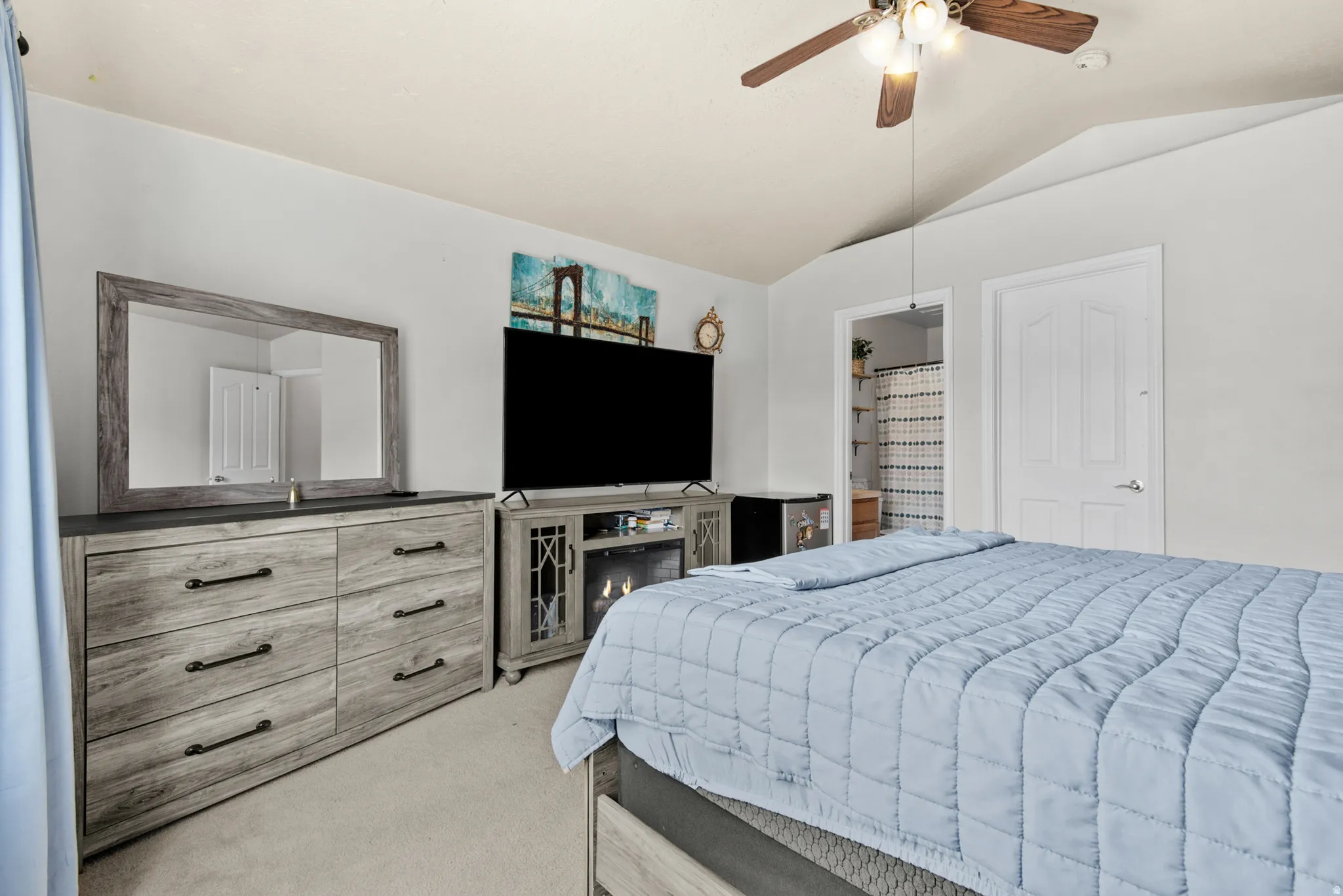 Vaulted ceiling with a ceiling fan, carpet flooring, and a private bath entry