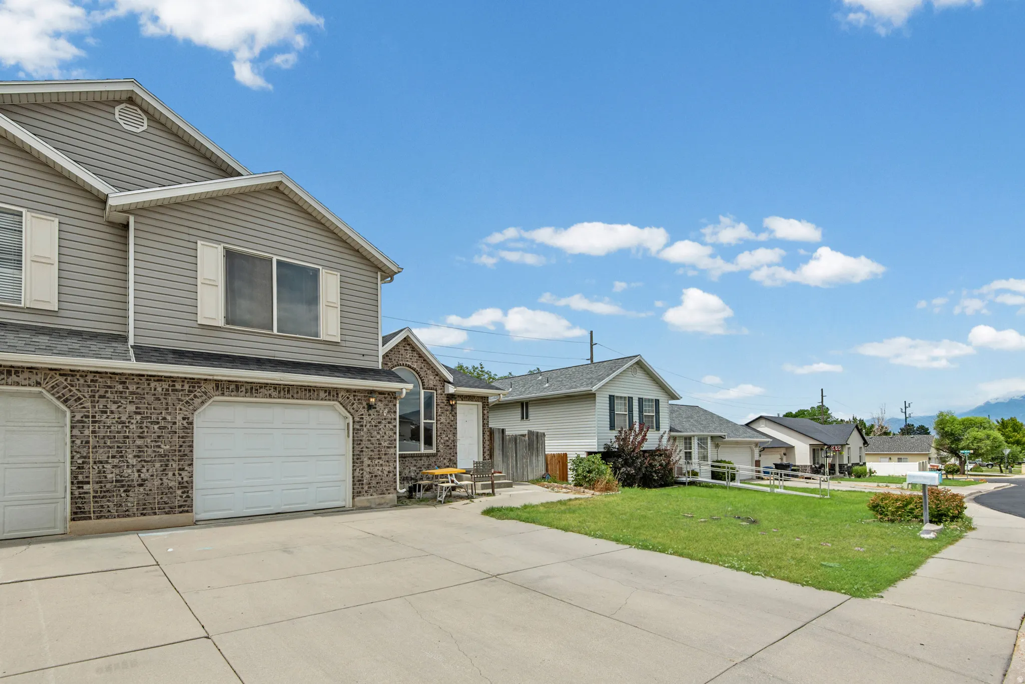 Two-story residence featuring a brick and siding exterior, two garage bays, and a concrete driveway