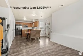 Open concept living space featuring wood-finish flooring, a kitchen with wood cabinetry, stainless steel appliances, and a central island with bar seating