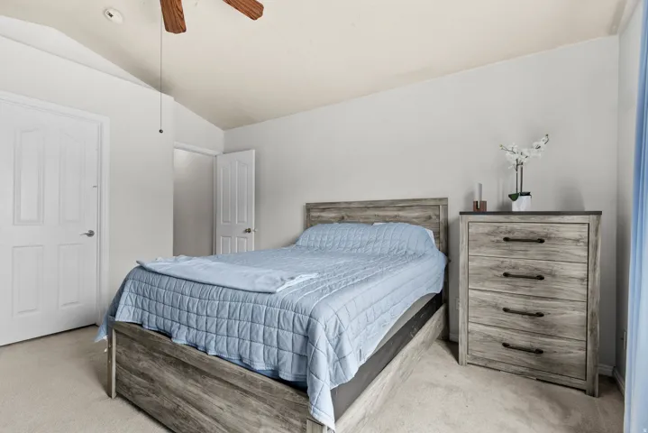 Bedroom featuring vaulted ceilings, carpet flooring, and a ceiling fan