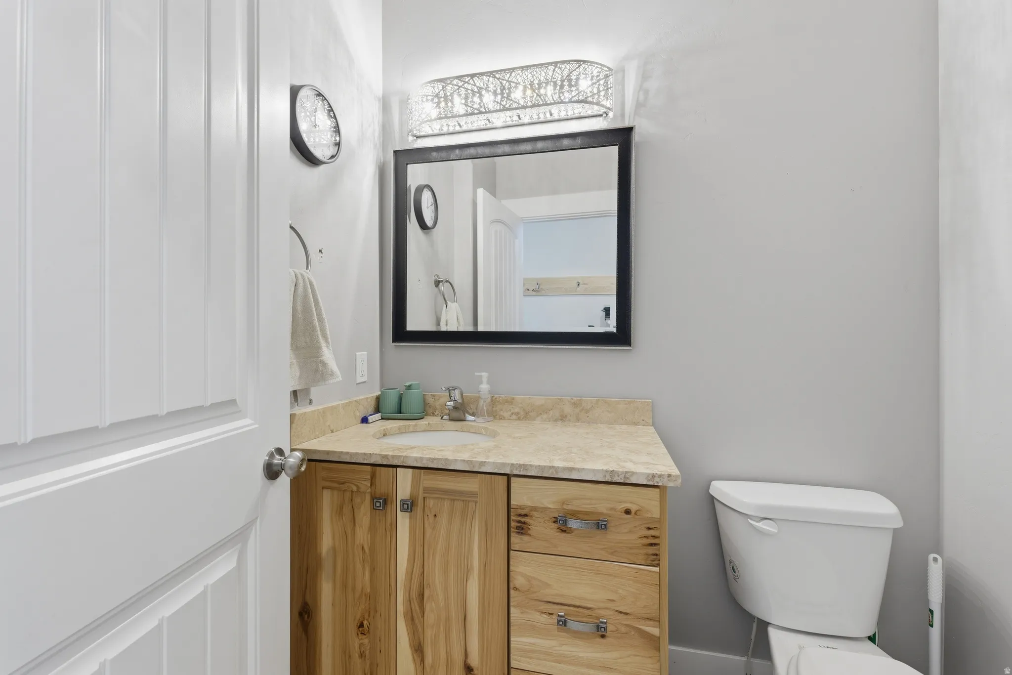 Powder room featuring a single vanity with wood-finish cabinetry, a light-toned countertop, and a rectangular undermount sink