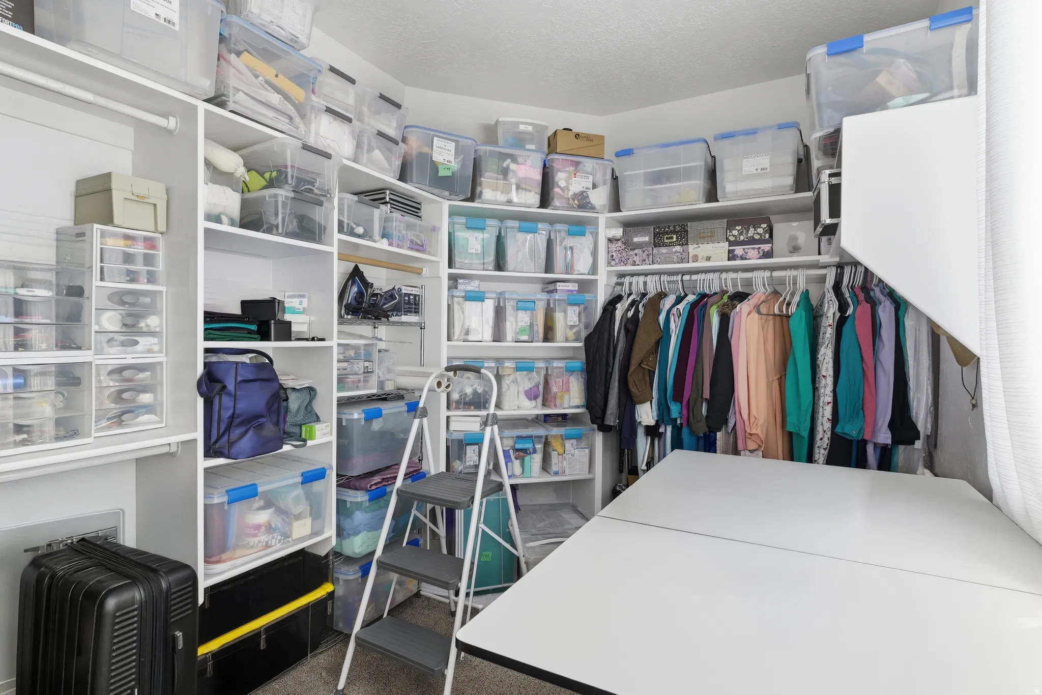 Customizable walk-in closet featuring extensive built-in shelving, integrated hanging rods, a dedicated work surface, and recessed lighting