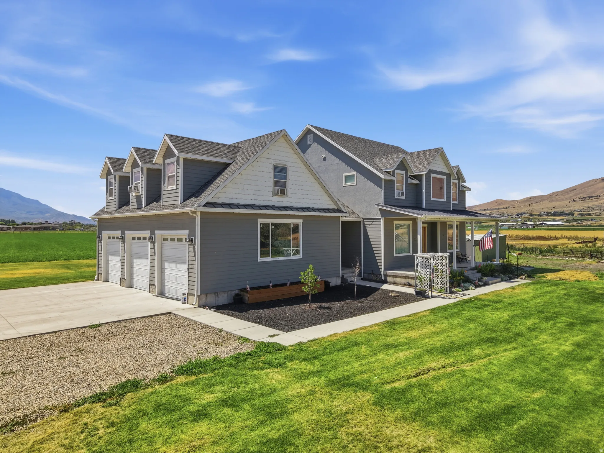 Two-story residence featuring grey siding, a covered front porch, and a three-car garage