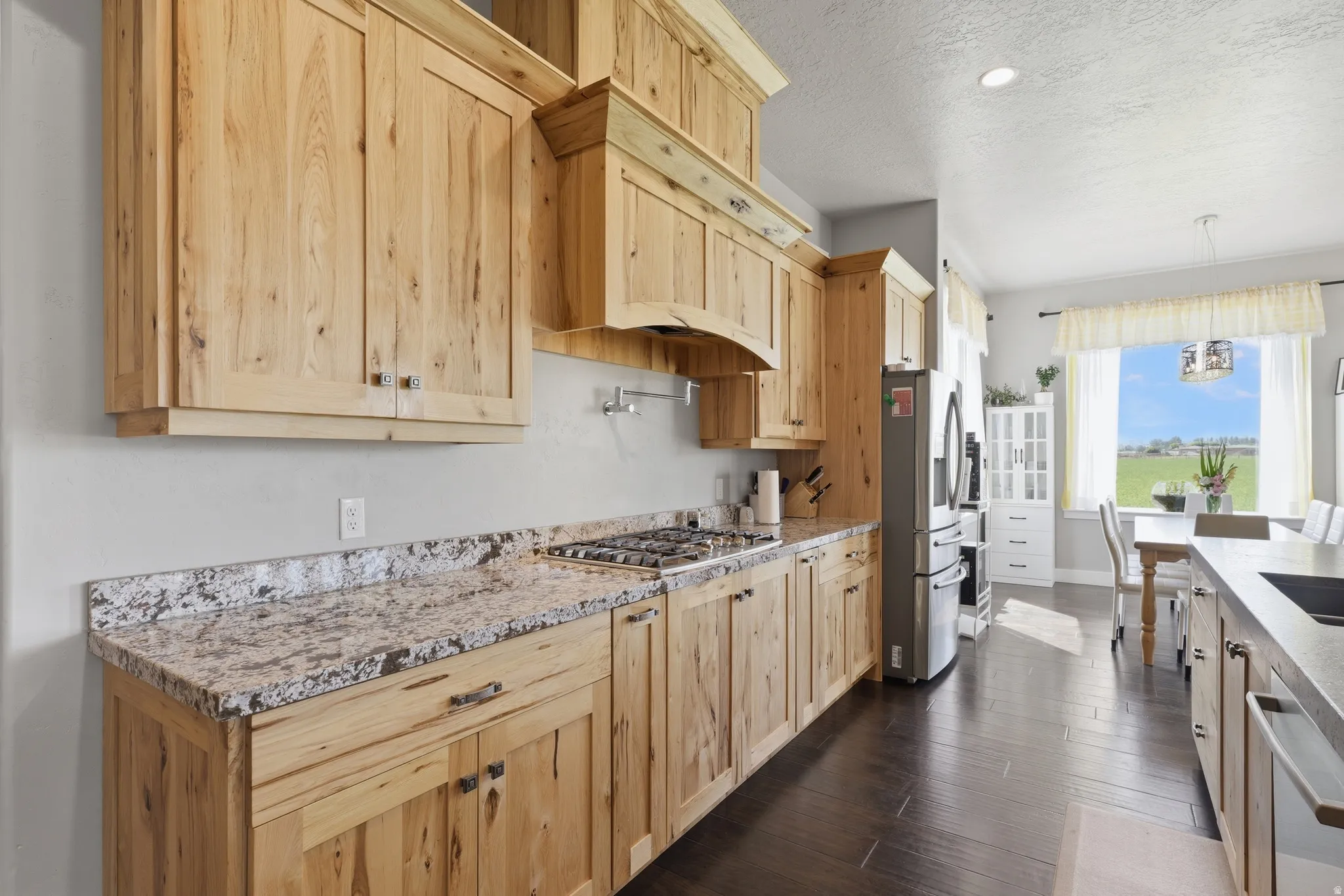Kitchen featuring light wood cabinetry, stone-finish countertops, stainless steel appliances, and dark wood-finish flooring