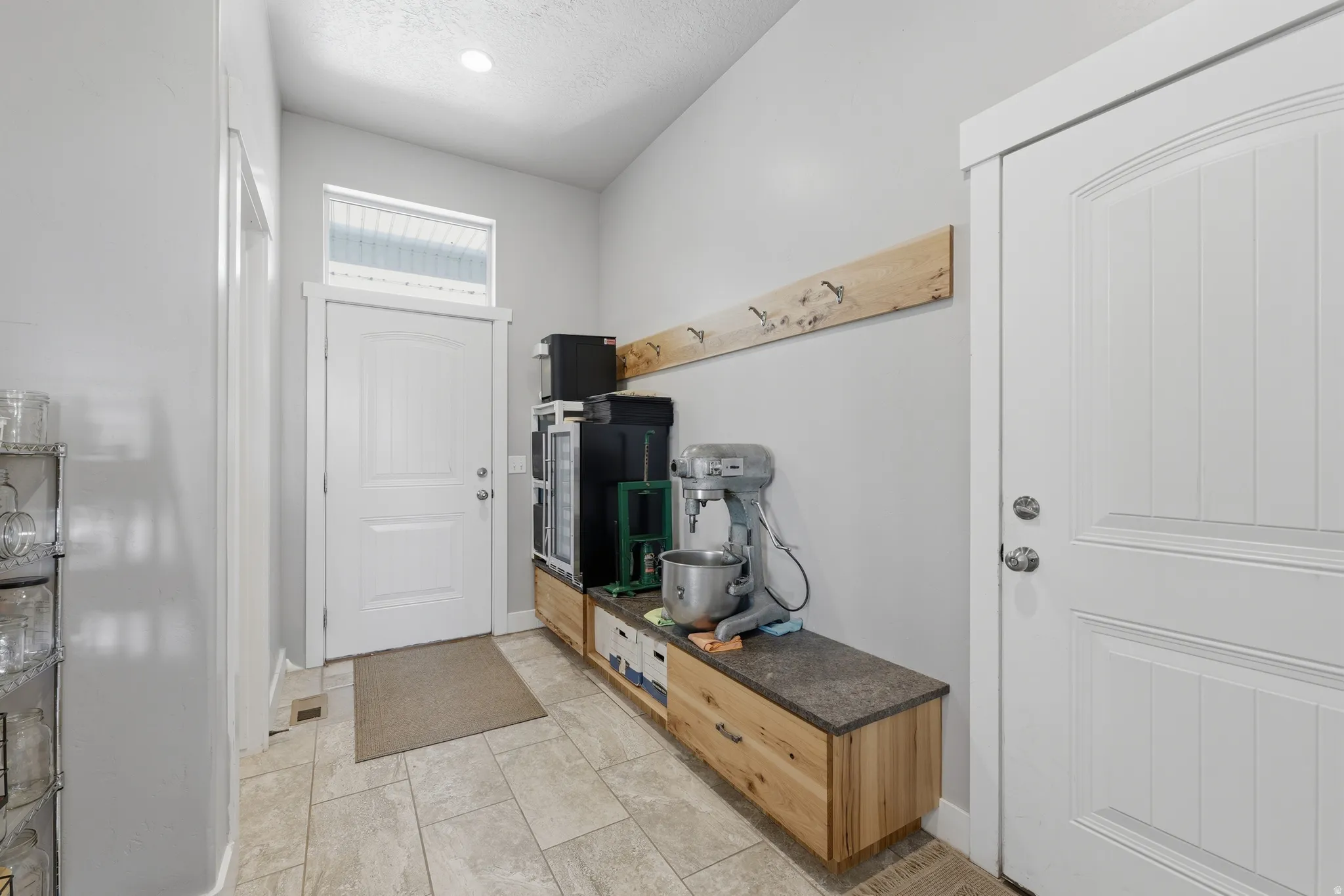 Mudroom entry featuring tiled flooring, a transom window above the door, and a built-in wood-finish storage bench with a dark countertop