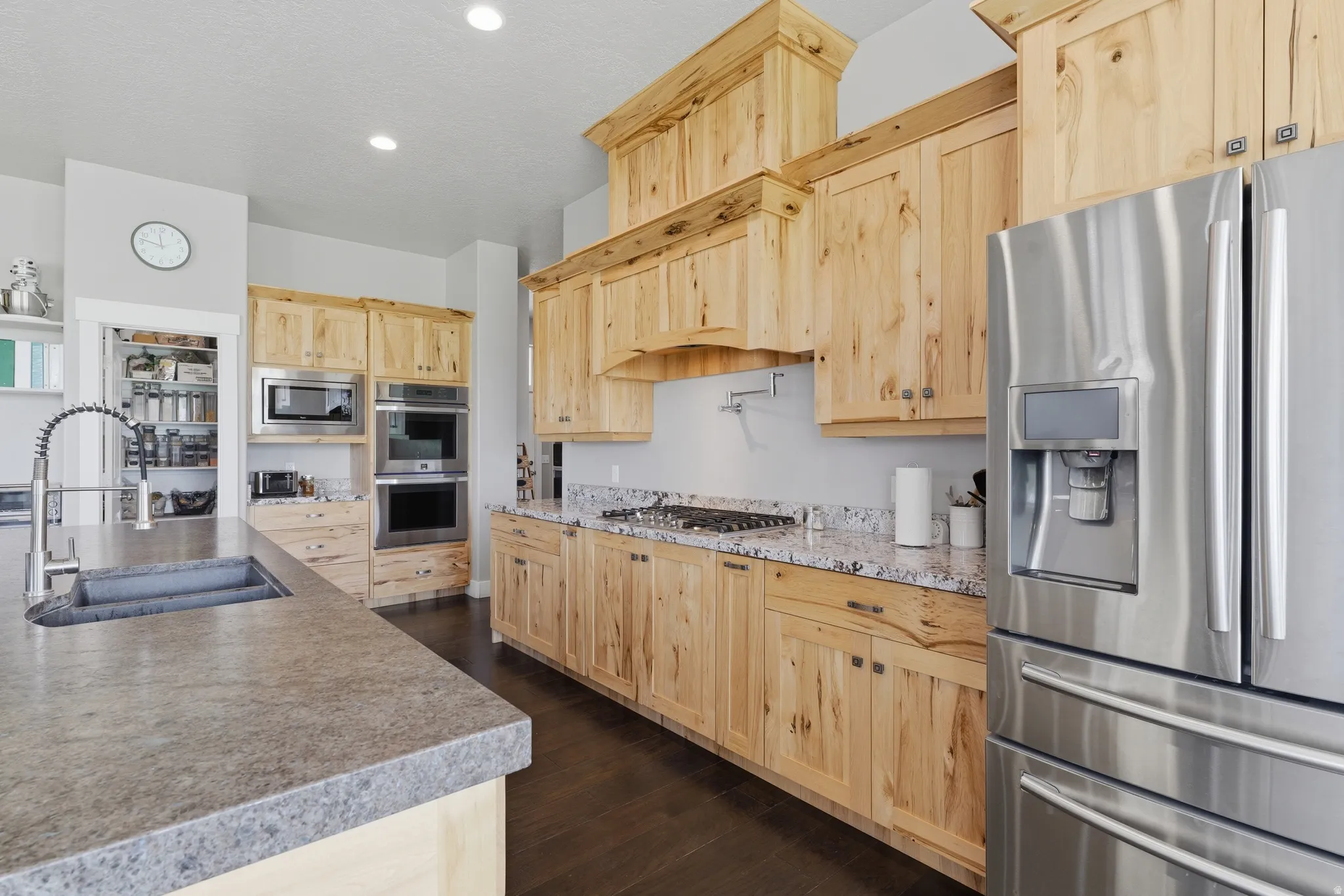Spacious kitchen featuring natural wood cabinetry, stainless steel appliances, a built-in double oven, an integrated microwave, and a gas cooktop