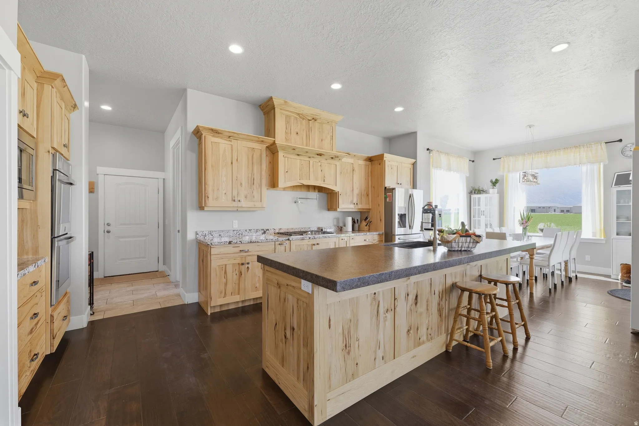 Spacious kitchen featuring light wood cabinetry and a large island with a composite countertop