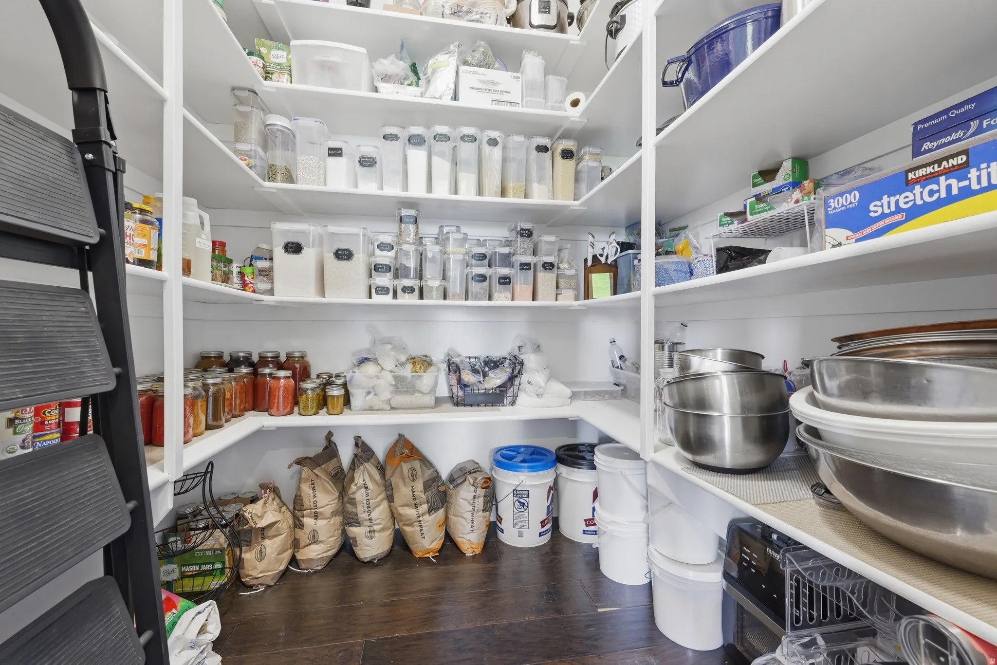 Walk-in pantry featuring extensive white shelving and wood-finish flooring