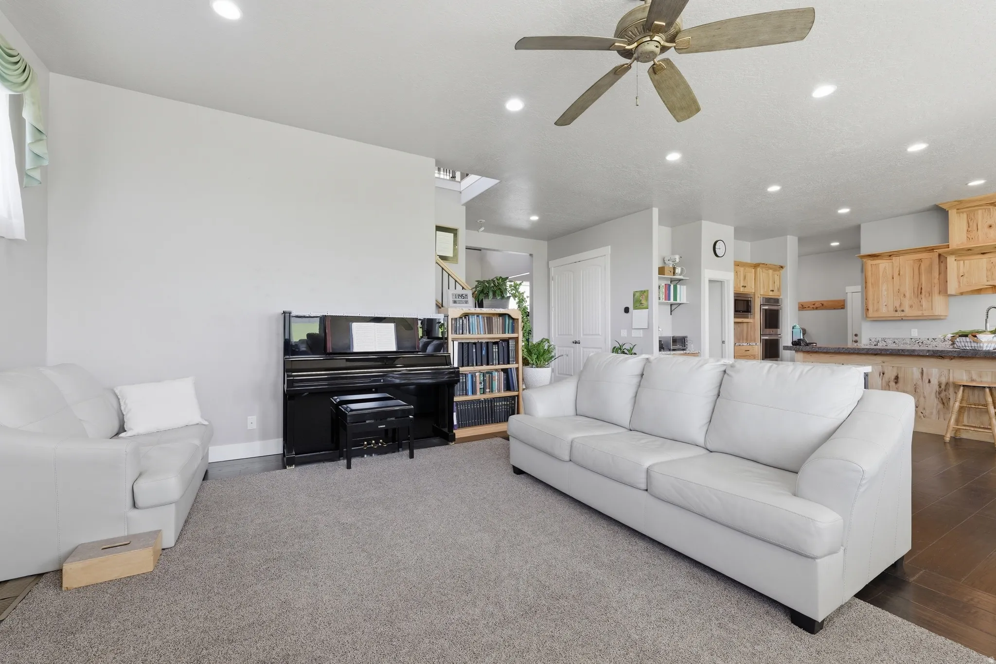 Open-concept living area featuring a ceiling fan, recessed lighting, and carpet flooring