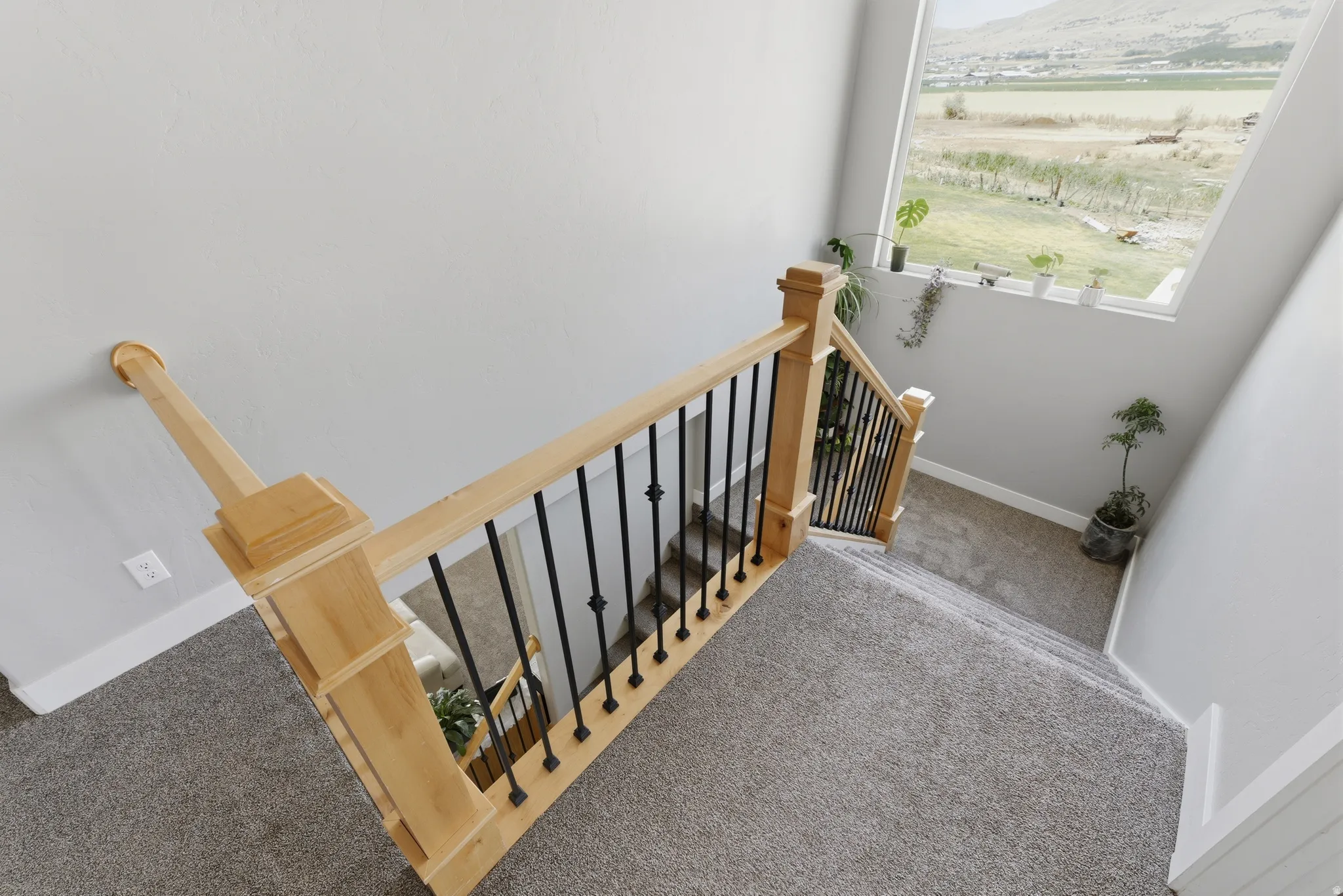 Staircase featuring natural wood newel posts and handrails with black metal balusters