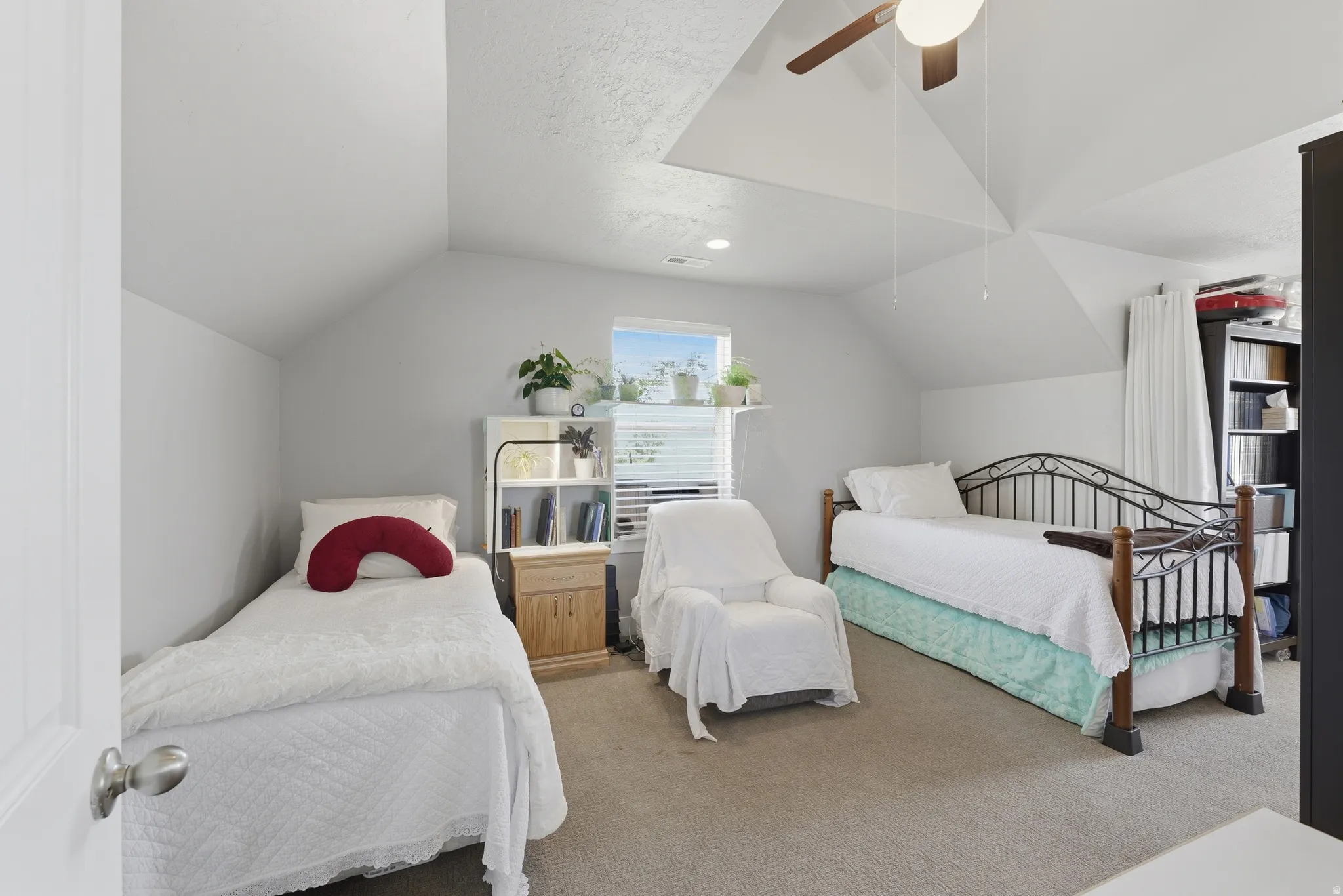 Attic space featuring sloped ceilings, a window with horizontal blinds, and carpeted flooring