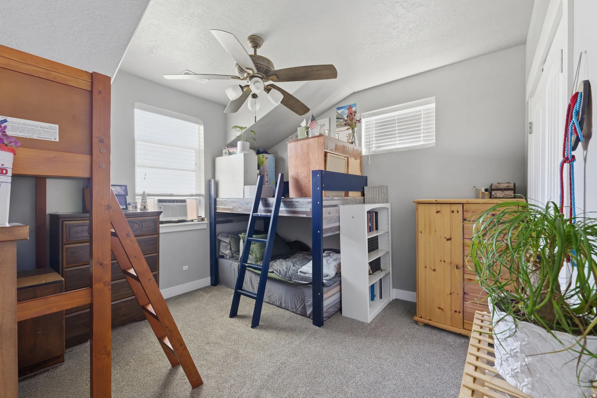 Carpeted room featuring light gray walls, a ceiling fan with integrated lighting, and two windows with blinds