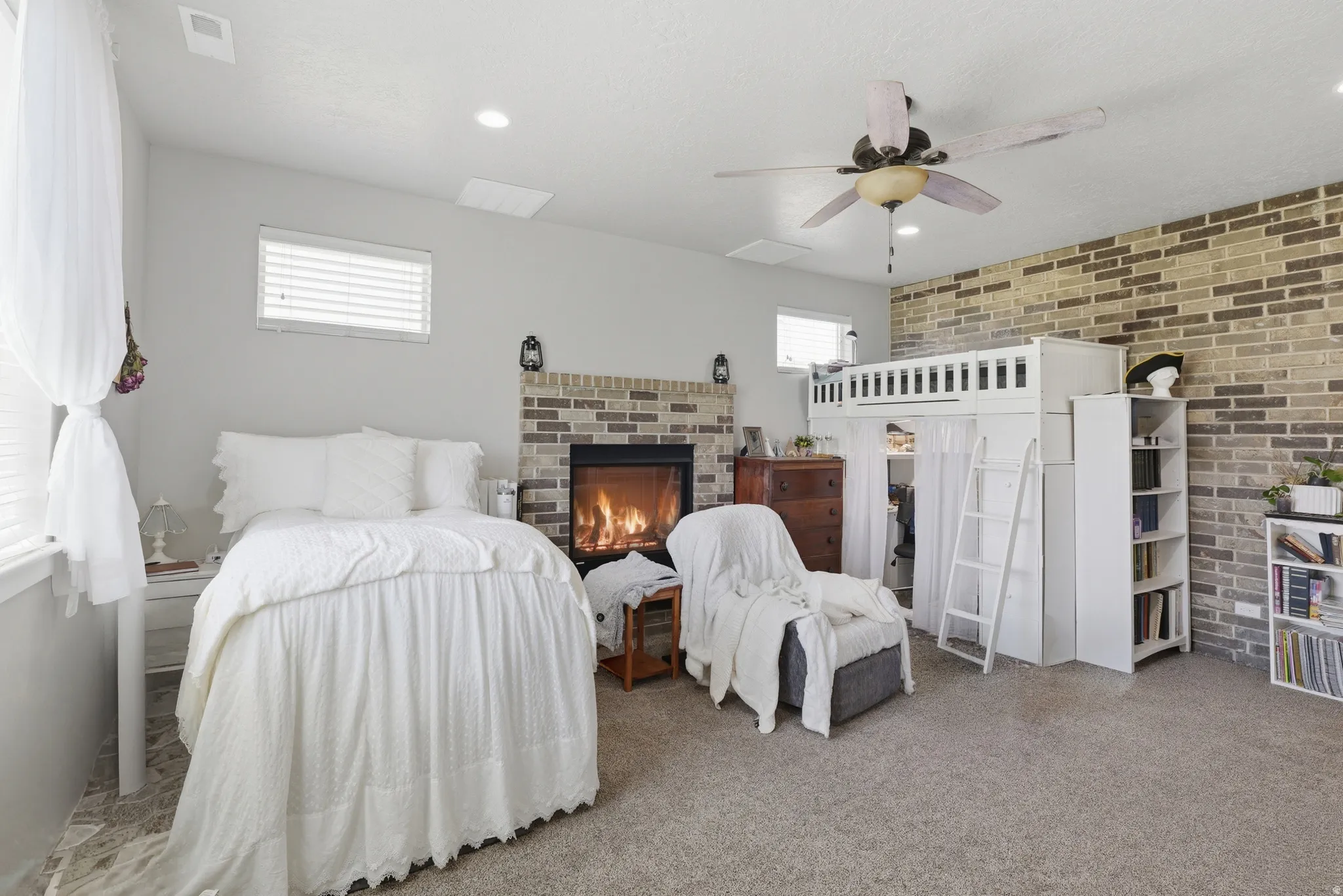 Master bedroom Carpeted room featuring a brick-surround fireplace, a ceiling fan, and multiple windows with blinds