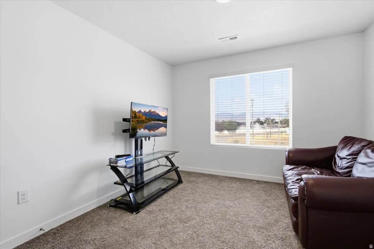 Carpeted room featuring a large window with horizontal blinds, providing natural illumination