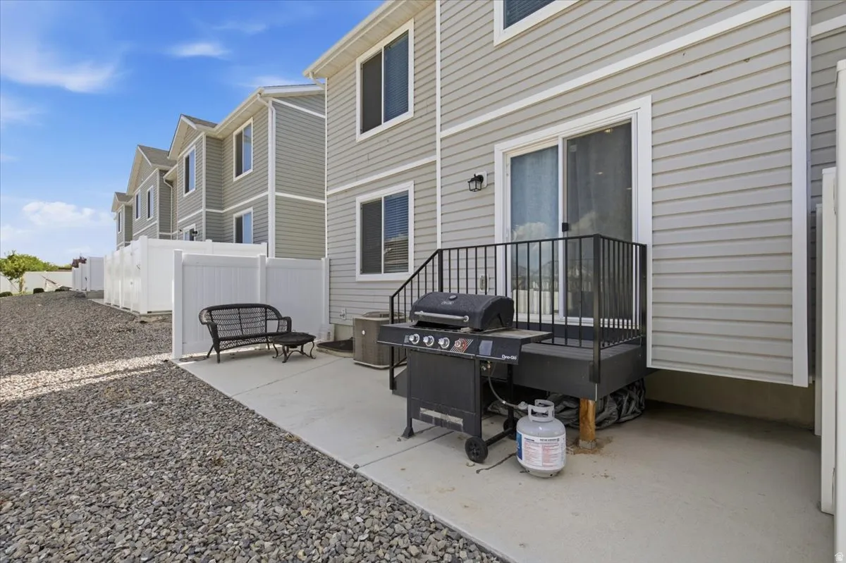 Rear patio featuring a sliding glass door, privacy fence, and gravel landscaping