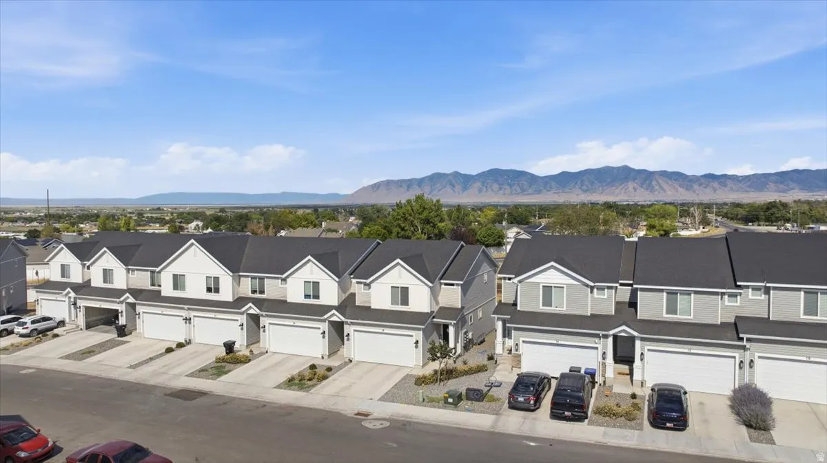 Row of contemporary townhomes featuring light gray siding, white trim, and dark shingle roofs