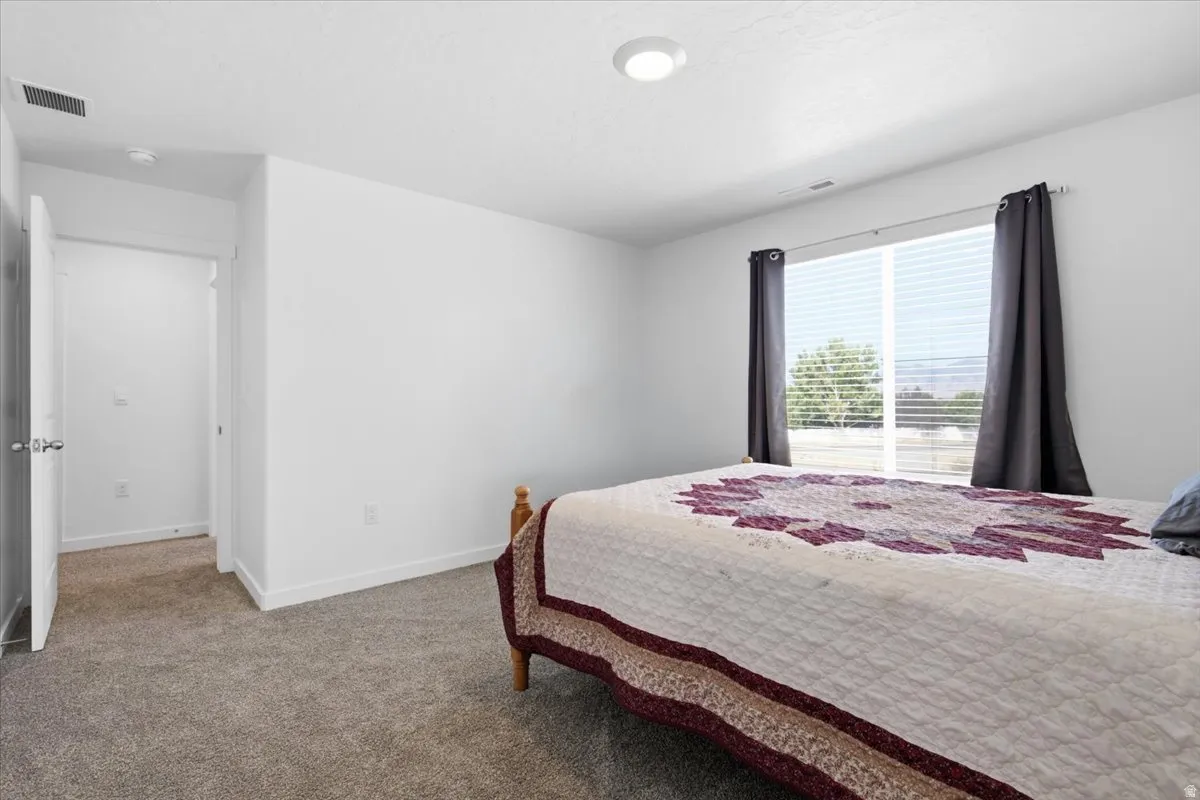 Carpeted room featuring a large window with horizontal blinds, recessed ceiling light, white walls, and white trim