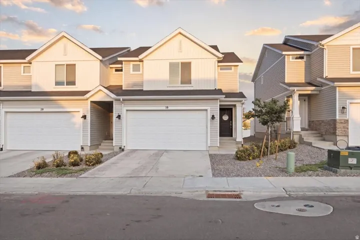 Modern townhouse exterior featuring light-toned siding, a peaked roofline, and an integrated single-car garage