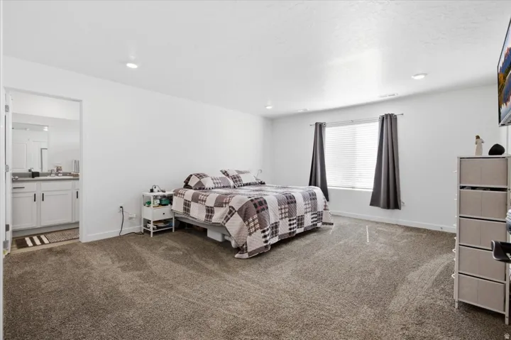 Carpeted bedroom with recessed lighting and a window featuring horizontal blinds