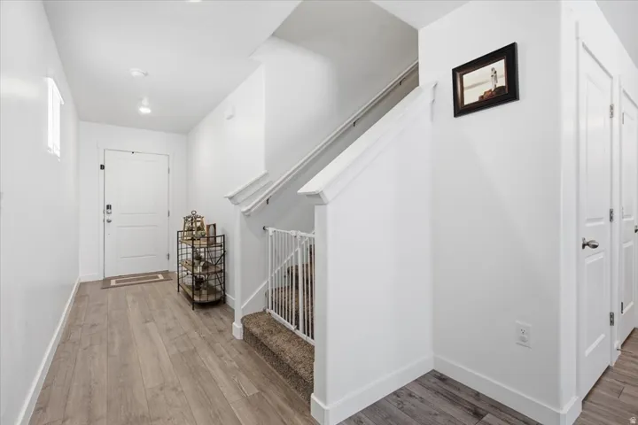 Entryway featuring wood-finish flooring, white walls, and a staircase with carpeted treads