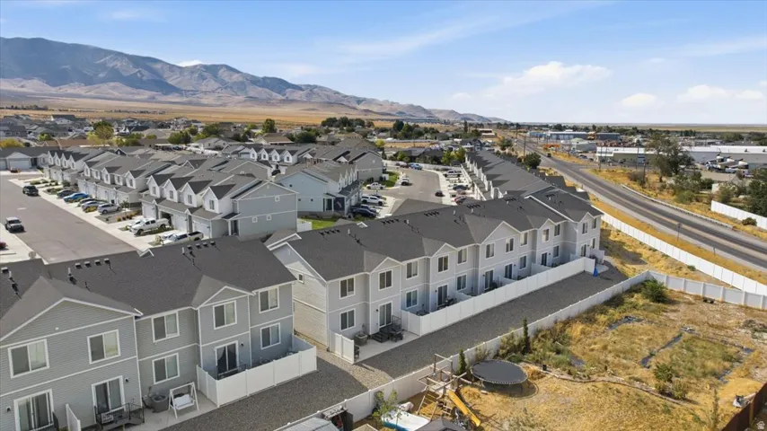 Aerial perspective of a multi-unit property featuring light gray siding, dark shingle roofs, and white fencing