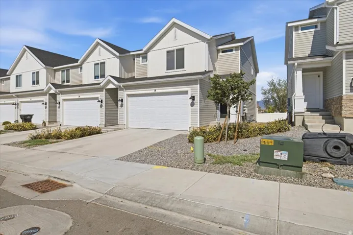 Contemporary townhome exterior featuring light-colored siding, contrasting trim, and a prominent two-car garage