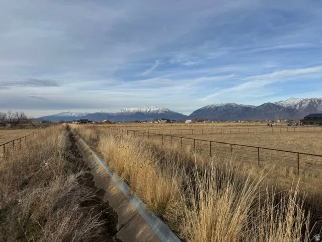 Expansive undeveloped land with a partial fence line and a concrete irrigation ditch