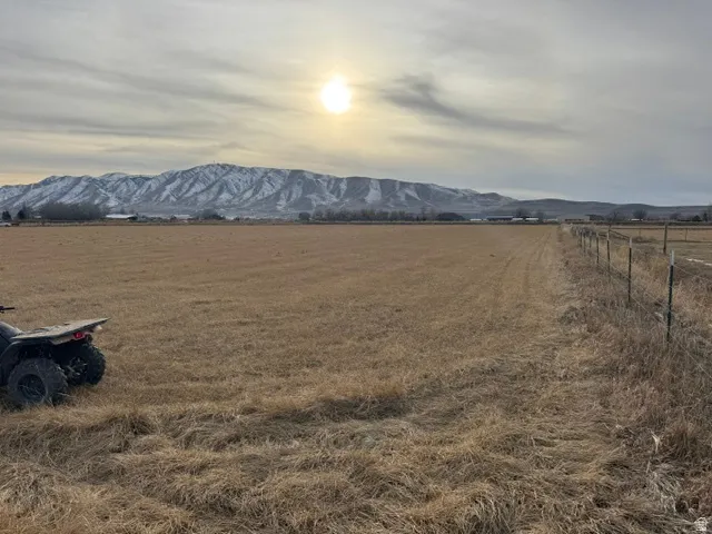 Expansive open land featuring a split rail fence and distant snow-capped mountains