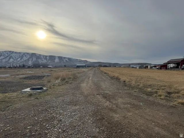 Expansive undeveloped land featuring a gravel path and distant snow-capped mountains