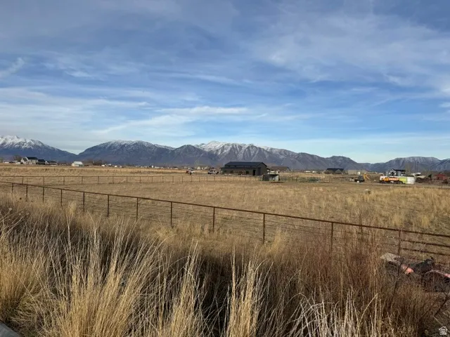 Expansive land parcel featuring a wire fence border and a mountainous backdrop