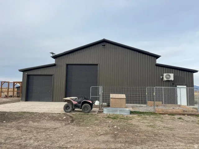 Metal-clad accessory building featuring a gabled roofline and two large roll-up garage doors