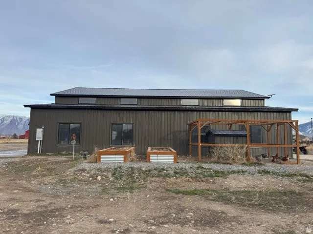 Metal-sided structure featuring a dark metal roof and multiple windows, with a visible mountain backdrop