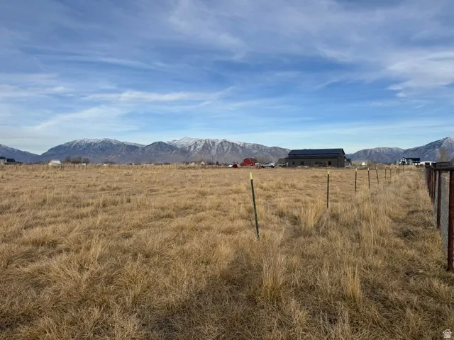 Expansive undeveloped land featuring a partial perimeter fence and distant snow-capped mountains