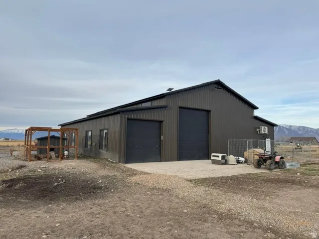 Metal-clad outbuilding featuring two large roll-up garage doors, multiple exterior windows, and a dark-pitched roof