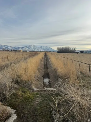 Agricultural land featuring a water canal, natural grasses, and a wire fence