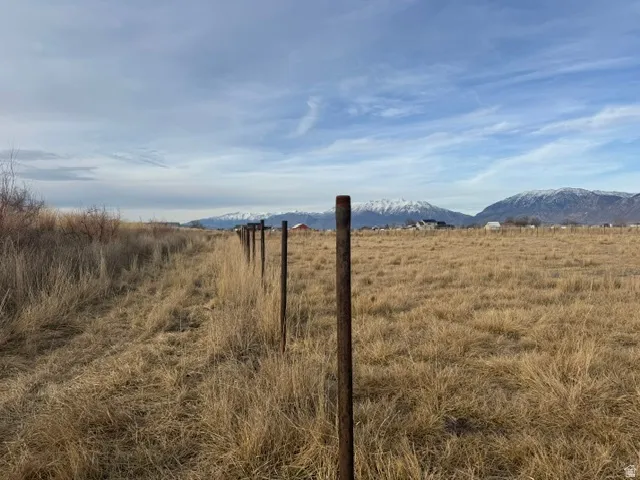 Expansive open land featuring a partial fence line and distant snow-capped mountains