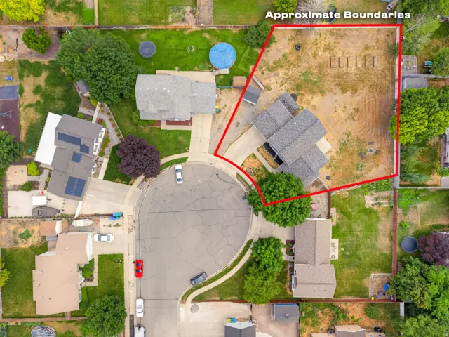Expansive corner lot featuring a detached residence, mature trees, and a paved driveway