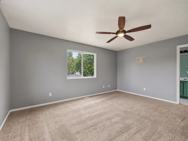 Spacious room with plush carpeting, neutral grey walls, and a white trim baseboard