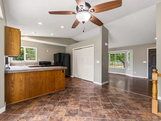 Kitchen with tile flooring and wood-finish cabinetry, featuring a ceiling fan, recessed lighting, and a partial breakfast bar