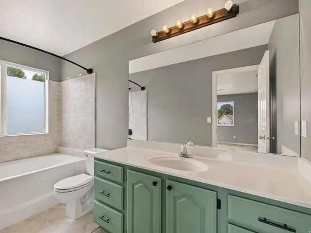 Bathroom featuring a light green vanity with multiple drawers, a white countertop, and an integrated sink