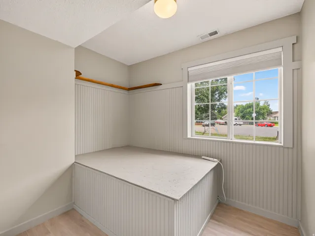 Room featuring a large window with white grilles, white beadboard paneling, and a built-in platform